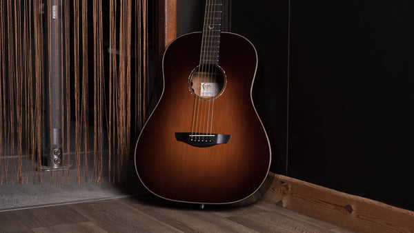 Acoustic guitar leaning against a wooden wall with a dark background