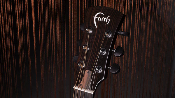 Guitar headstock with 'Faith' branding on a wooden background
